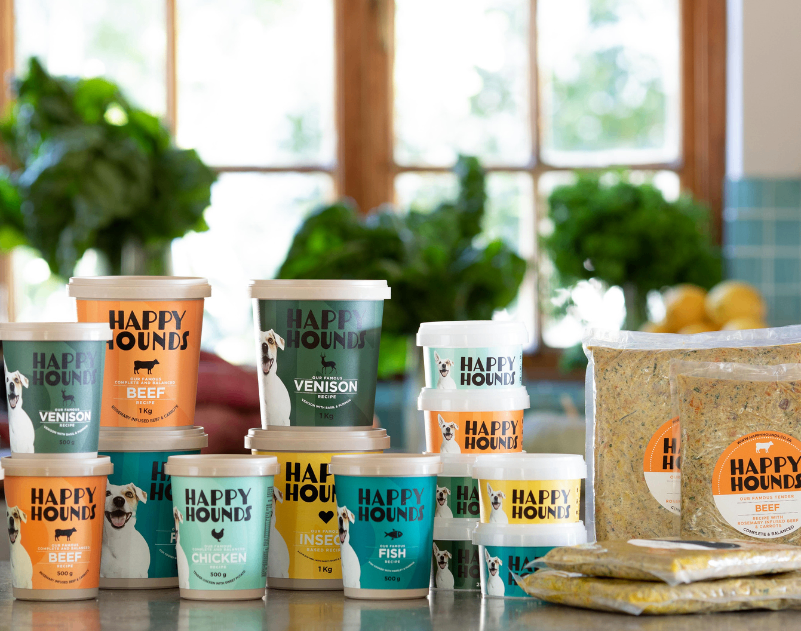 Happy Hounds tubs and vacuum bags of lightly cooked fresh food displayed on a counter